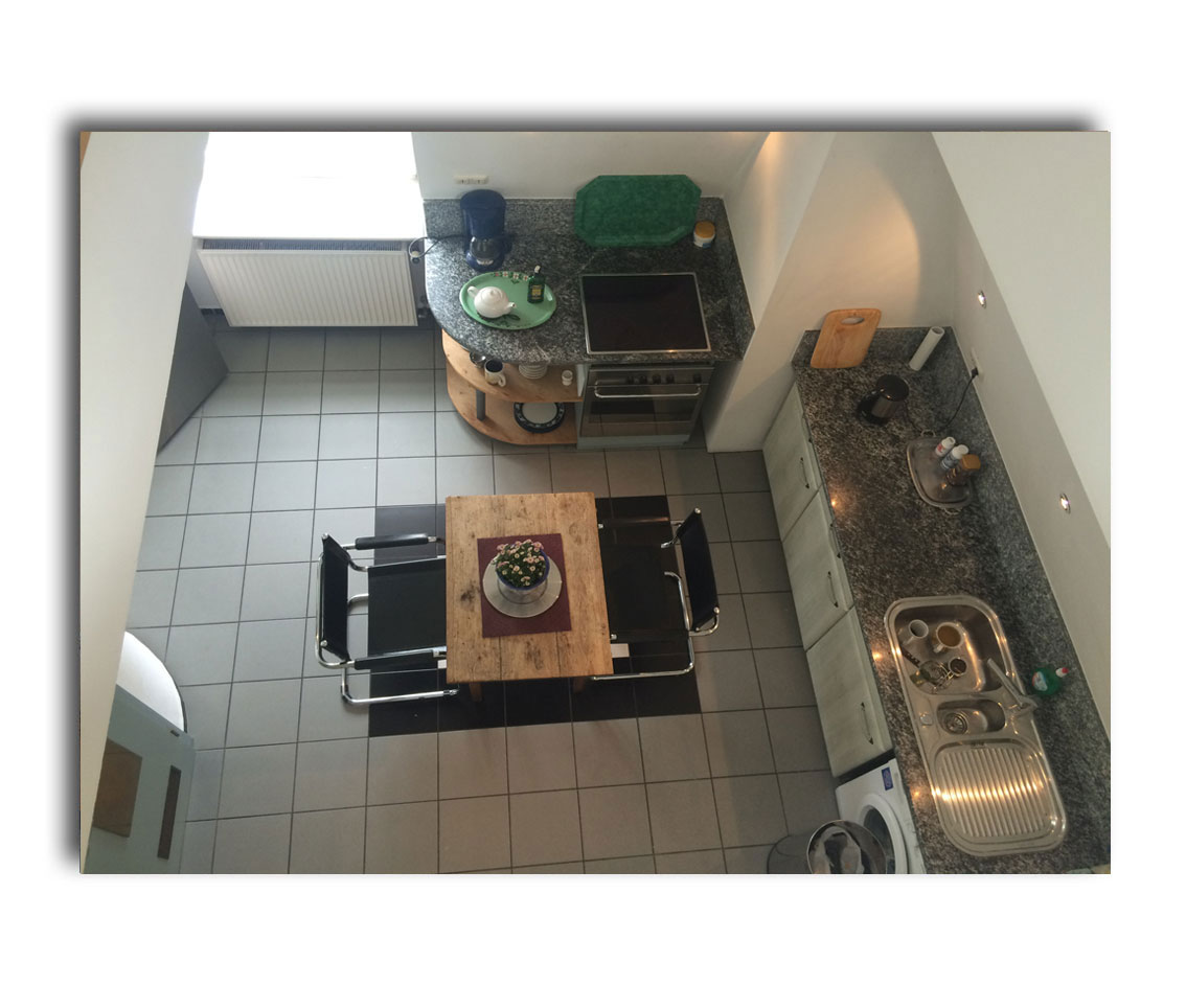 Blick von der Galerie in die Küche mit Herd, Kühlschrank und Waschmaschine